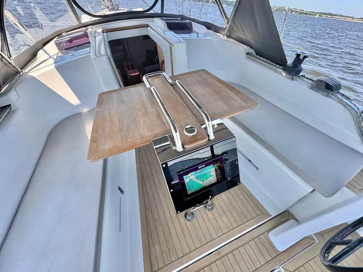 Ahyoka Yacht Photos Pics 2017 Hanse 345 yacht cockpit with wooden table and navigation display, overlooking the water.