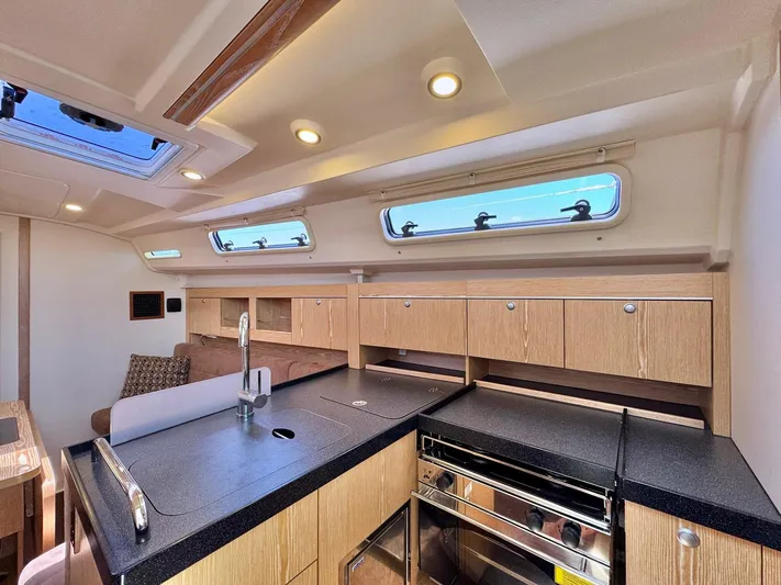 Ahyoka Yacht Photos Pics Interior of 2017 Hanse 345 yacht, featuring modern kitchen with wood cabinetry and skylight.