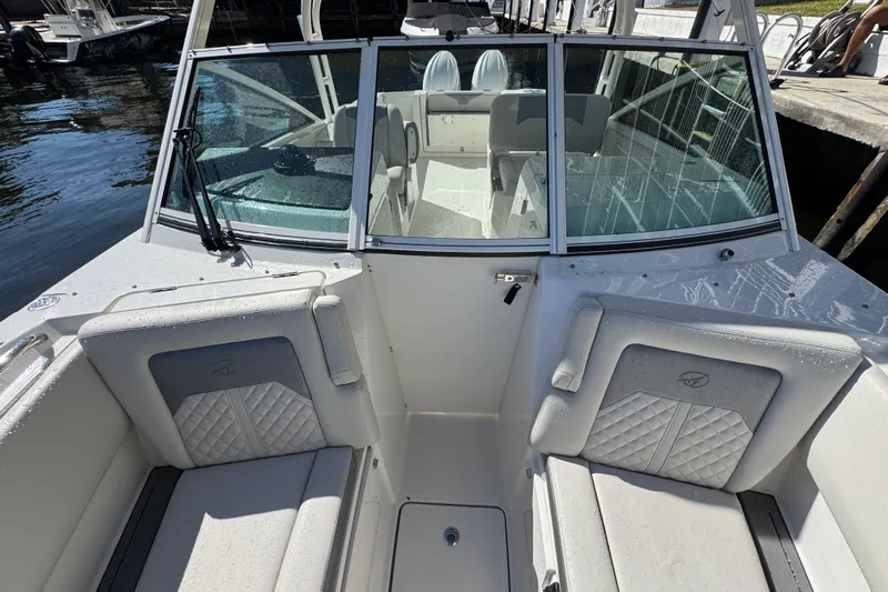  Yacht Photos Pics 2025 Sailfish 276 DC boat interior with cushioned seating and windshield, docked by the water.