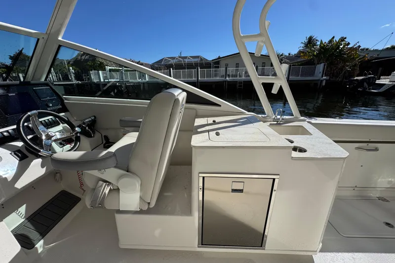  Yacht Photos Pics 2025 Sailfish 276 DC boat interior with helm, seating, and storage, docked by waterfront homes.