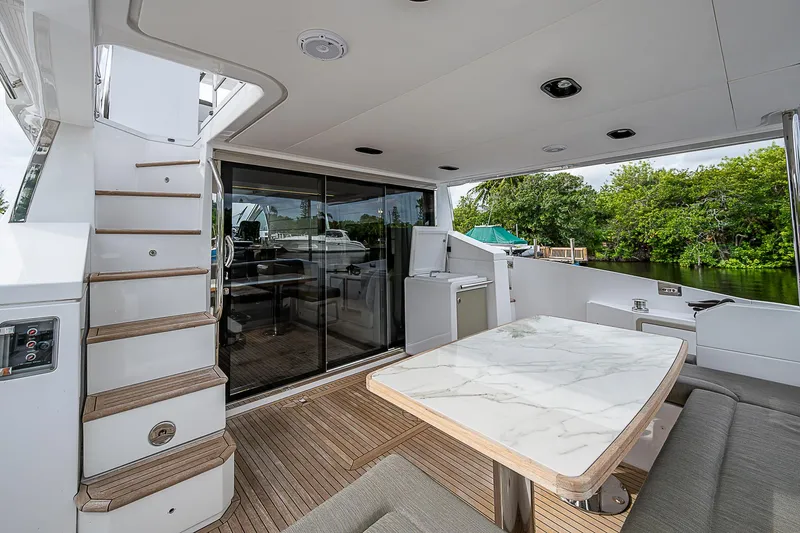 Evado Yacht Photos Pics 2020 Azimut 66 yacht deck with marble table, stairs, and sliding glass doors.