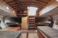 Interior of 1905 PLYMS Prototype Sloop, featuring wooden benches and skylights.