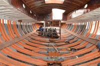 Interior view of 1905 PLYMS Prototype Sloop under restoration, showcasing wooden ribs and structure.