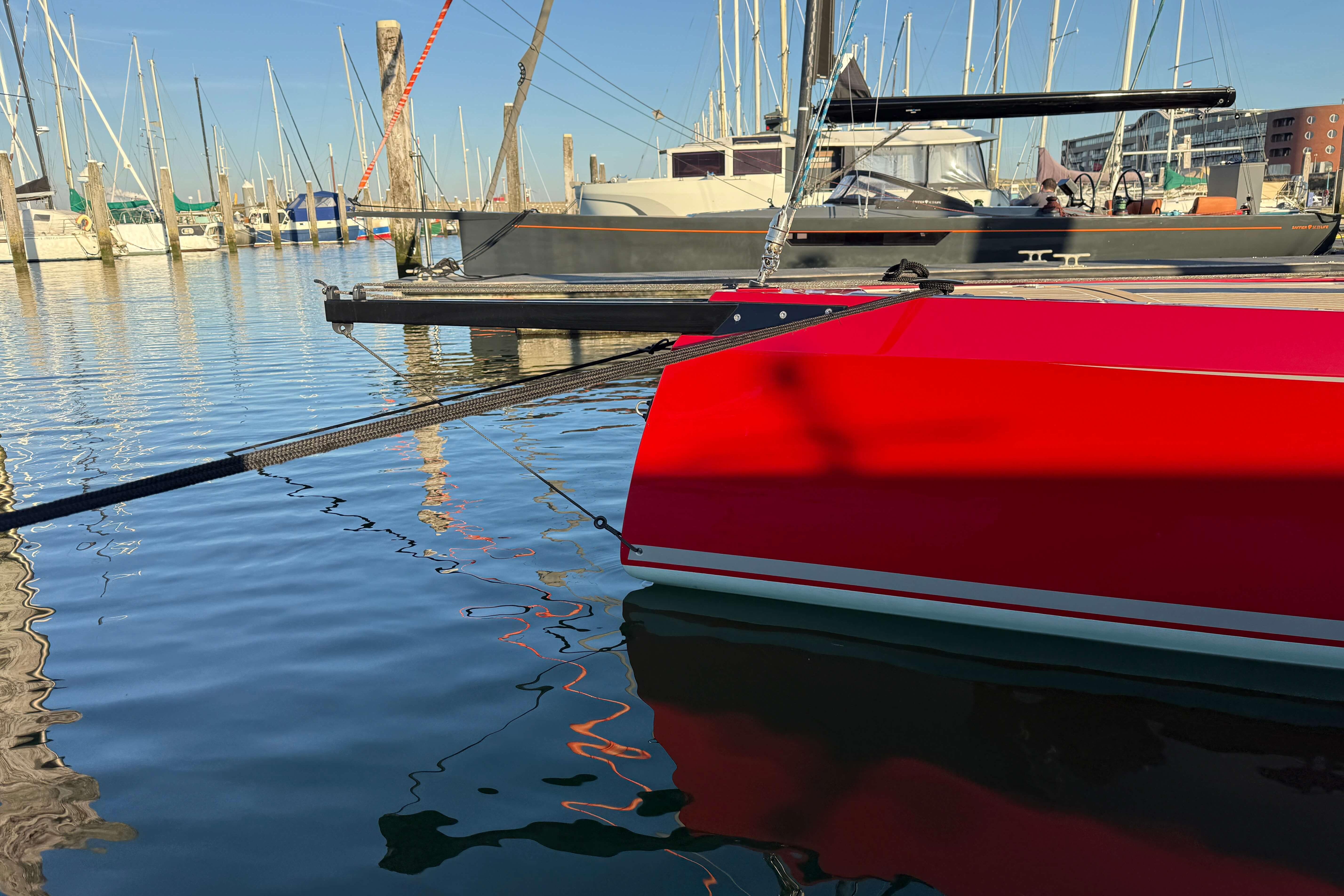 2024 Saffier SE 24 Lite sailboat in marina, vibrant red hull reflecting on water.