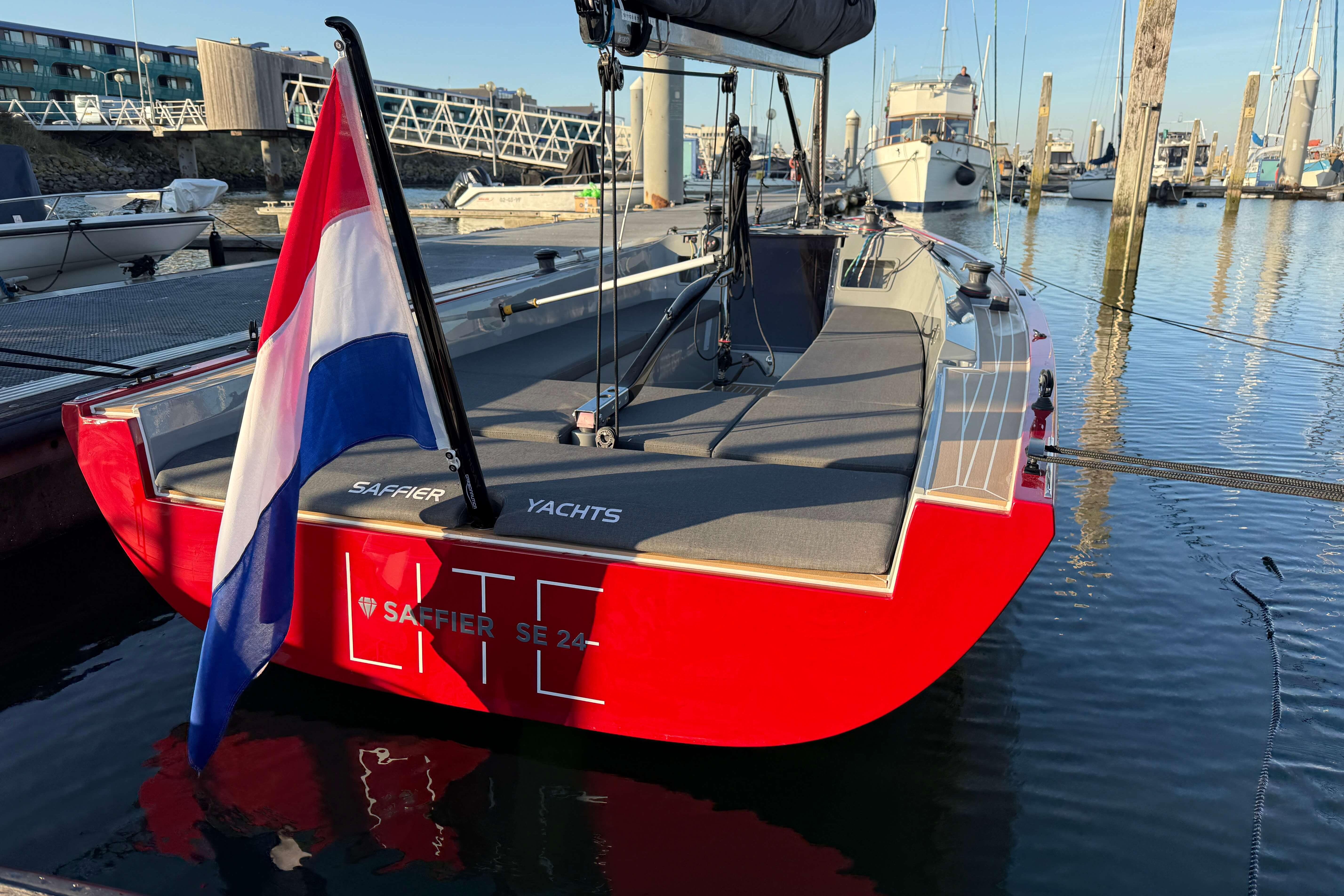 2024 Saffier SE 24 Lite sailboat docked, featuring a vibrant red hull and national flag.