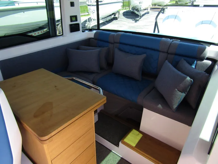 Empoleon Yacht Photos Pics 2025 Axopar 37XC CROSS CABIN BRABUS interior with blue seating and wooden table.