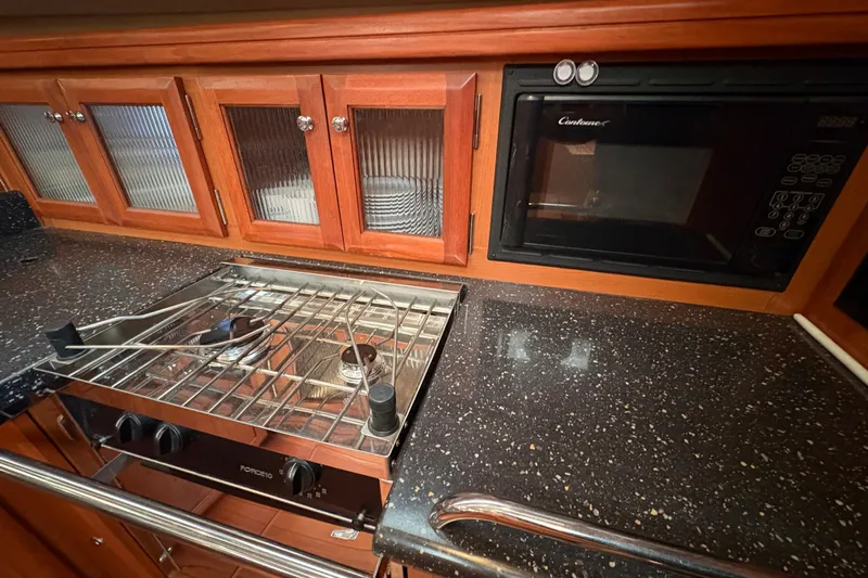 Tru Blu Yacht Photos Pics Galley kitchen in 2010 Hunter 39 yacht with stove, microwave, and wooden cabinets.