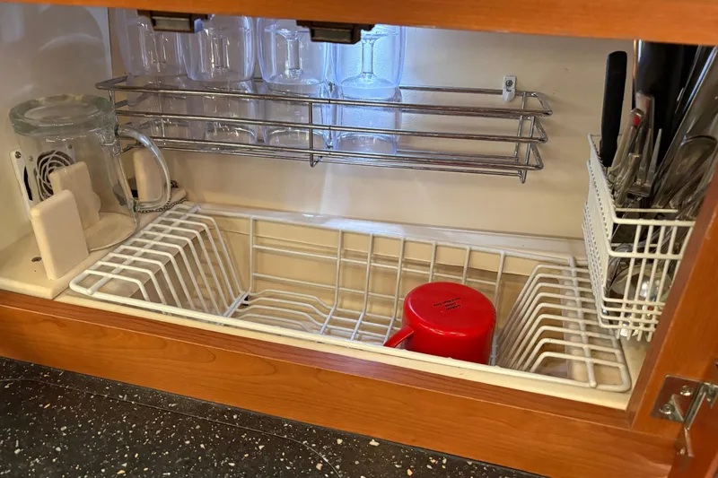 Tru Blu Yacht Photos Pics Under-sink dish rack with glasses, utensils, and a red mug in a Hunter 39, 2010 model.