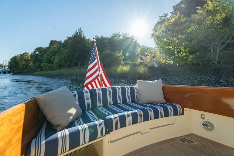Timeless (name Reserved) Yacht Photos Pics 2015 Hinckley Picnic Boat MK III with striped seating, American flag, and scenic water view.