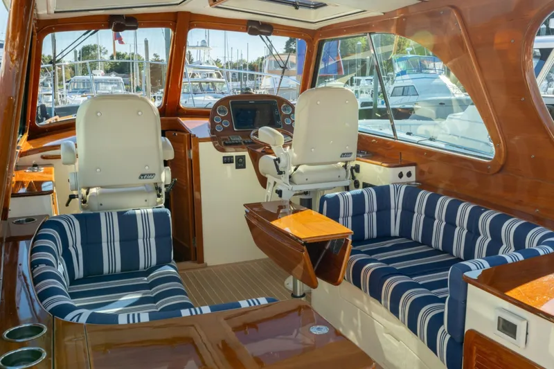 Timeless (name Reserved) Yacht Photos Pics Interior of 2015 Hinckley Picnic Boat MK III with striped seating and wooden finishes.