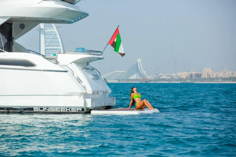Outlaw Yacht Photos Pics Sunseeker Manhattan 55 yacht with person relaxing, Dubai skyline in background, 2015 model.