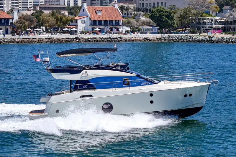 The Riviera Yacht Photos Pics 2017 Monte Carlo MC5S yacht cruising near a scenic coastal town.