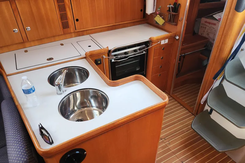 Runaway Yacht Photos Pics 2005 Elan 40 yacht kitchen with dual sinks, stove, and wooden cabinetry.