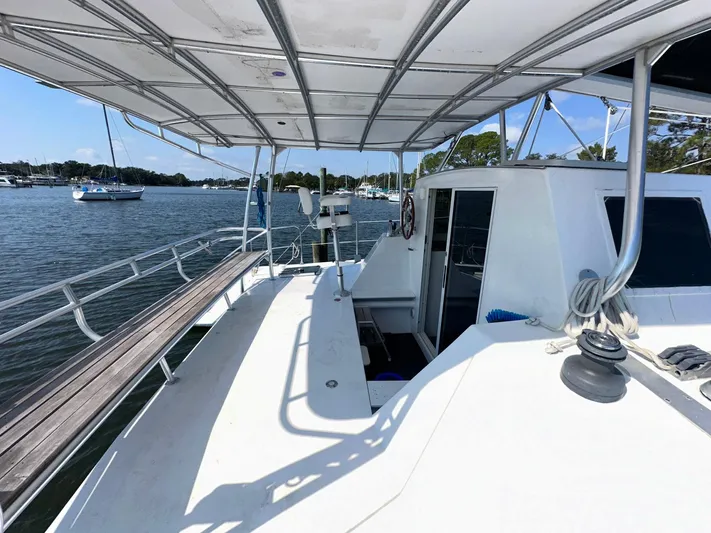 Sola Fide Yacht Photos Pics 1993 Russell Yachts Crowther sailboat deck with canopy, docked in a serene marina.