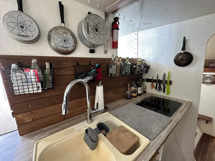 Sola Fide Yacht Photos Pics Compact yacht kitchen with sink, stove, hanging pans, and organized storage. Russell Yachts Crowther, 1993 model.