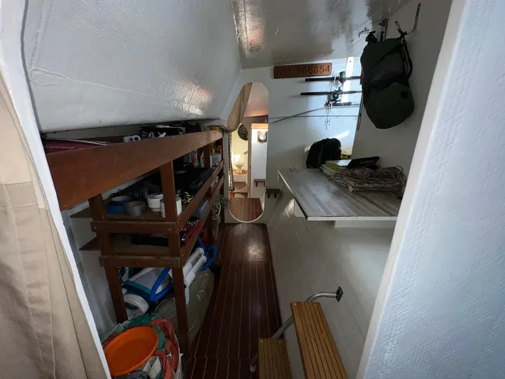 Sola Fide Yacht Photos Pics Interior of 1993 Russell Yachts Crowther, featuring storage shelves and wooden flooring.