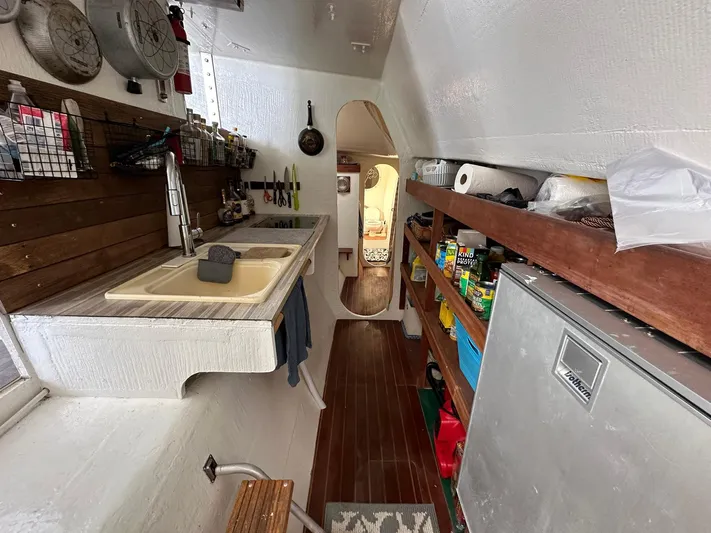 Sola Fide Yacht Photos Pics Interior of 1993 Russell Yachts Crowther, featuring a compact kitchen with wooden accents and storage.