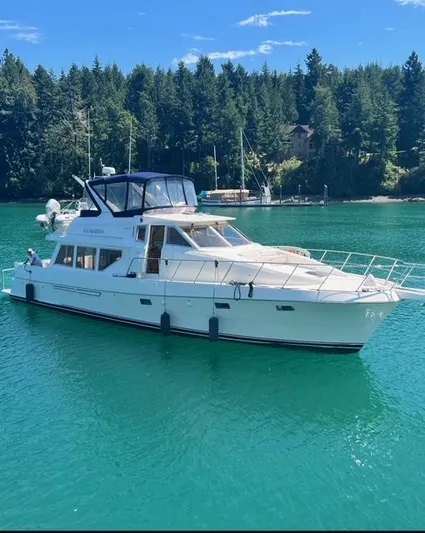  Yacht Photos Pics 2000 McKinna 57 Pilothouse yacht on serene water with forested background.