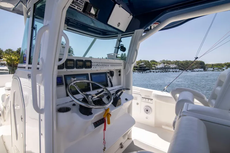 Outta Hand Yacht Photos Pics 2009 Everglades 350CC boat cockpit with steering wheel and controls, overlooking a scenic waterfront.