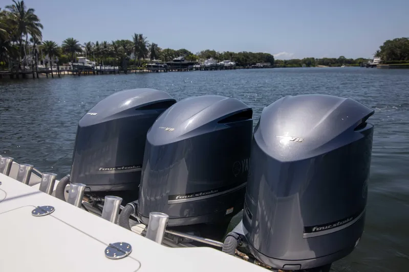 Outta Hand Yacht Photos Pics Triple Yamaha outboard engines on a 2009 Everglades 350CC boat, docked by a scenic waterfront.