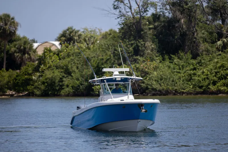 Outta Hand Yacht Photos Pics 2009 Everglades 350CC boat on calm water with lush greenery background.