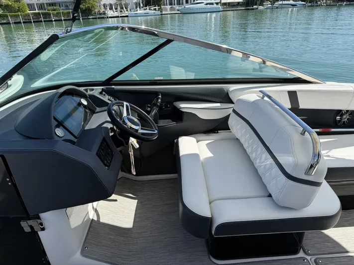  Yacht Photos Pics 2019 Regal 29 OBX boat interior with steering wheel and seating, docked by the water.