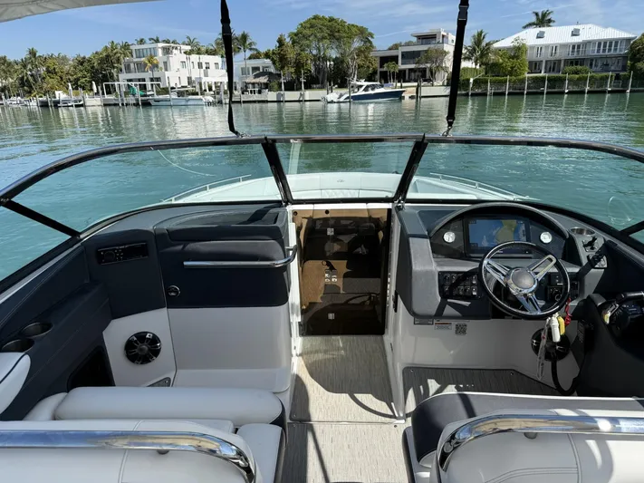  Yacht Photos Pics 2019 Regal 29 OBX boat interior with steering wheel, docked by waterfront homes.