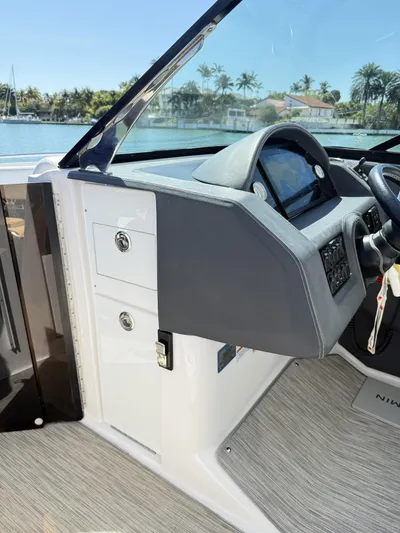  Yacht Photos Pics 2019 Regal 29 OBX boat dashboard with steering wheel and control panel, docked by palm trees.