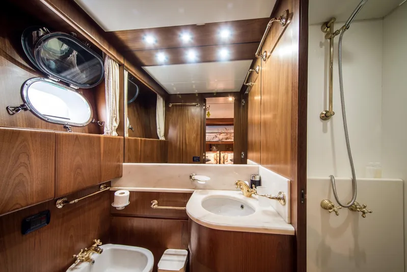  Yacht Photos Pics Luxurious bathroom in 1998 Sanlorenzo SL72 yacht with wood paneling and gold fixtures.