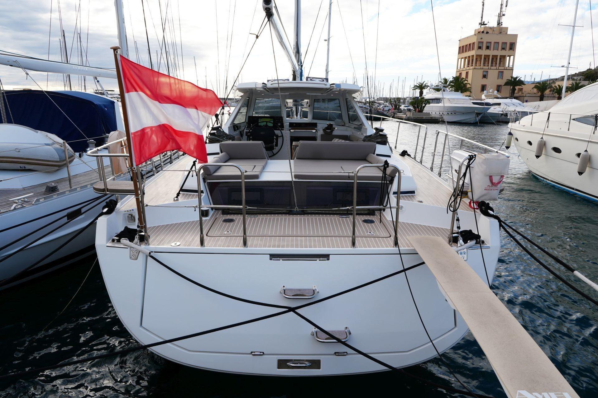 2023 Amel 50 yacht docked, featuring a spacious deck and vibrant flag.