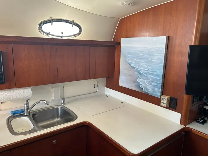  Yacht Photos Pics 1997 Tiara Yachts 4000 Express interior kitchen with sink, wooden cabinets, and ocean artwork.