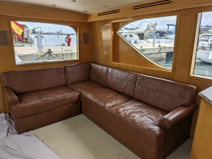  Yacht Photos Pics Interior of 2001 Hatteras 70 Convertible yacht with brown leather sofa and marina view.