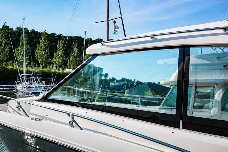  Yacht Photos Pics 2021 Regal 36 Grande Coupe yacht docked, reflecting clear blue sky and lush greenery.