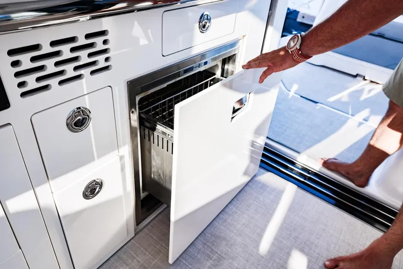  Yacht Photos Pics 2021 Regal 36 Grande Coupe yacht interior with open drawer and person reaching inside.