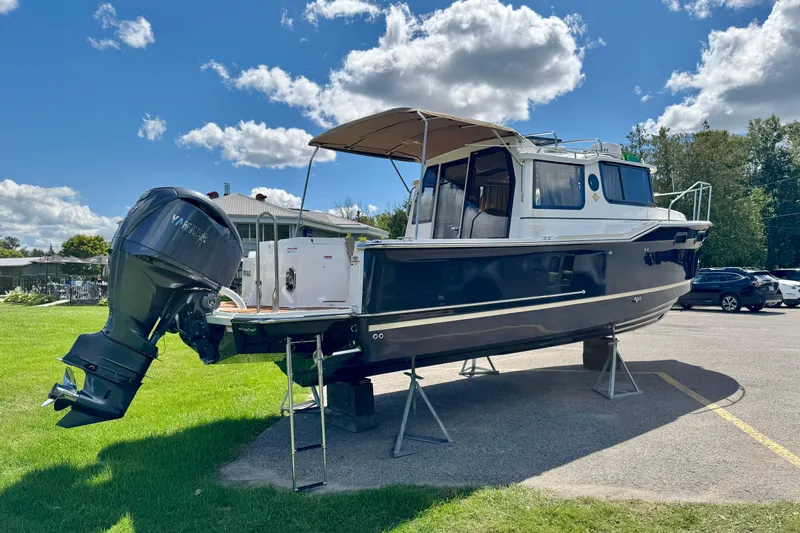  Yacht Photos Pics 2025 Ranger Tugs R-27 boat on display with outboard motor, under a sunny sky.