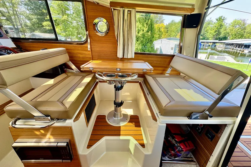  Yacht Photos Pics Interior of 2025 Ranger Tugs R-27 boat with seating and table, featuring wood accents.