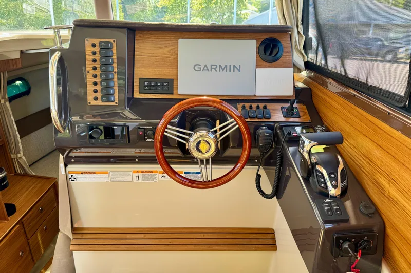  Yacht Photos Pics 2025 Ranger Tugs R-27 helm with Garmin navigation, wooden accents, and modern controls.