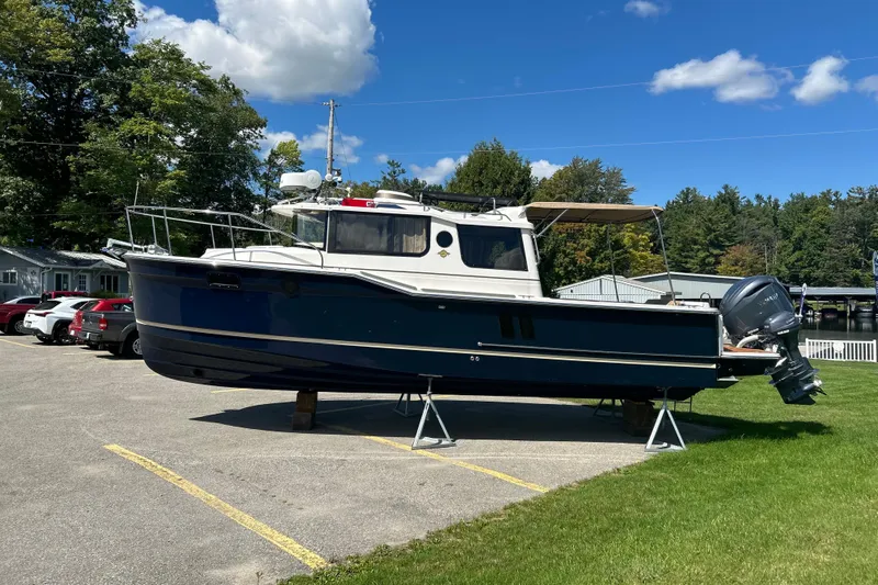  Yacht Photos Pics 2025 Ranger Tugs R-27 boat on stands, parked outdoors under a clear blue sky.