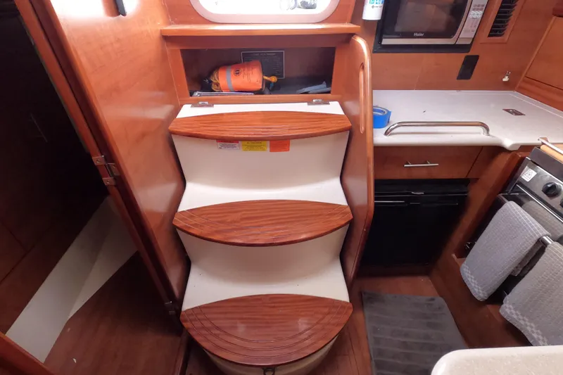 Moon Shadow Yacht Photos Pics Interior of 2013 Marlow-Hunter e33 sailboat with wooden steps and compact kitchen area.