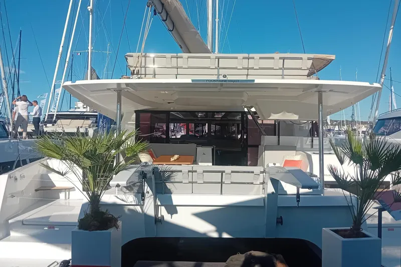  Yacht Photos Pics 2024 Fountaine Pajot Tanna 47 catamaran, docked with elegant outdoor seating and potted plants.