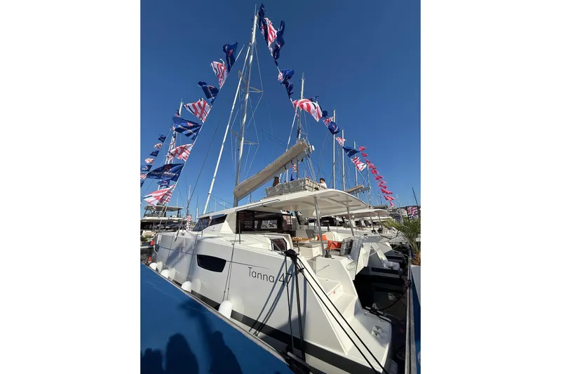  Yacht Photos Pics 2024 Fountaine Pajot Tanna 47 catamaran with flags, docked under clear blue sky.