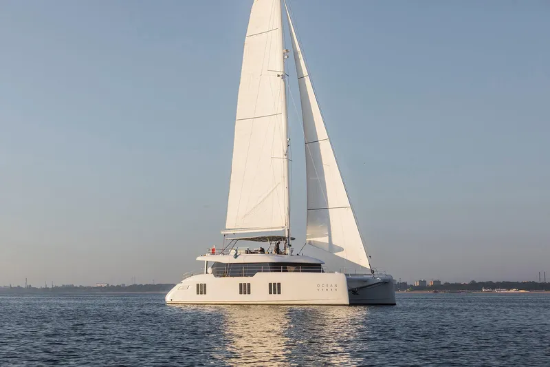  Yacht Photos Pics 2026 Sunreef 70 sailing catamaran on calm waters at sunset.