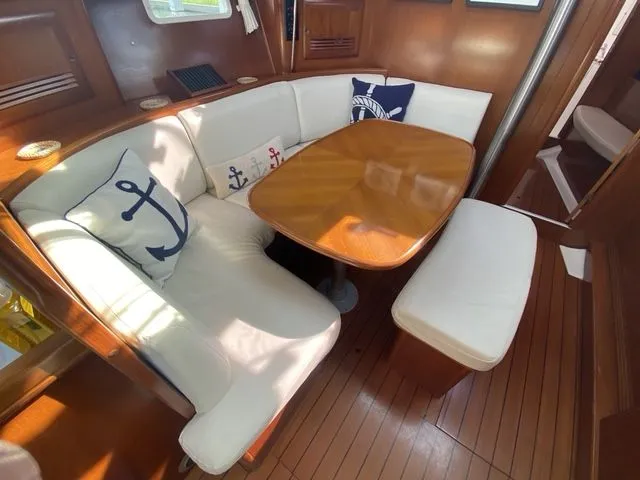 Axis Mundi Yacht Photos Pics Interior of 2002 Beneteau 393 yacht with cushioned seating and nautical-themed pillows.