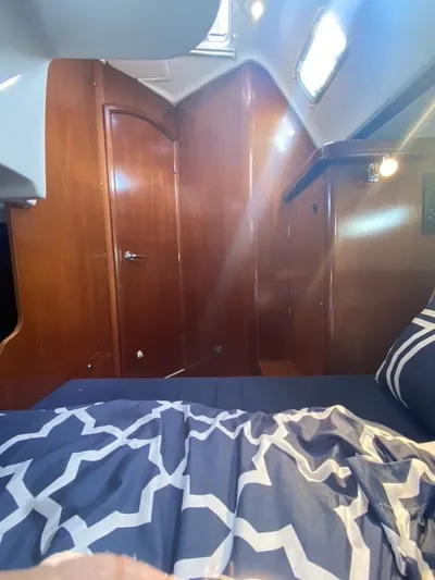 Axis Mundi Yacht Photos Pics Interior cabin of 2002 Beneteau 393 yacht with wooden finish and patterned bedding.