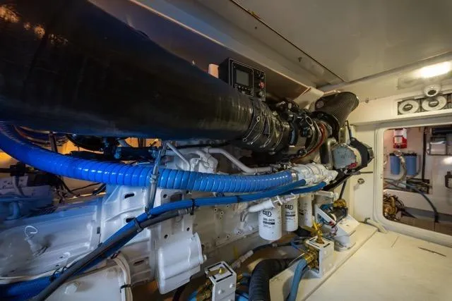  Yacht Photos Pics Engine room of a 1997 Garlington Convertible boat, showcasing complex machinery and blue hoses.