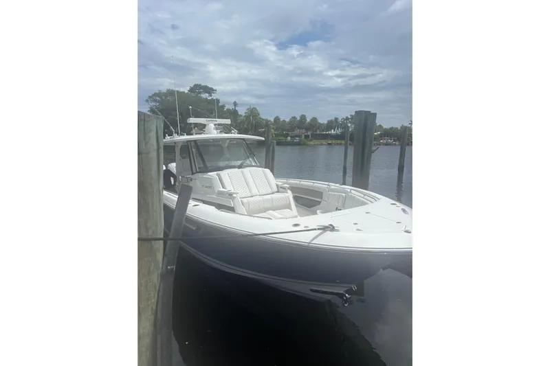  Yacht Photos Pics 2021 Pursuit S 378 Sport boat docked on a calm river under cloudy skies.