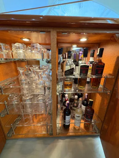 Obelix Yacht Photos Pics Luxurious bar cabinet on 2006 Riviera 60 Flybridge yacht, featuring glasses and premium liquor bottles.