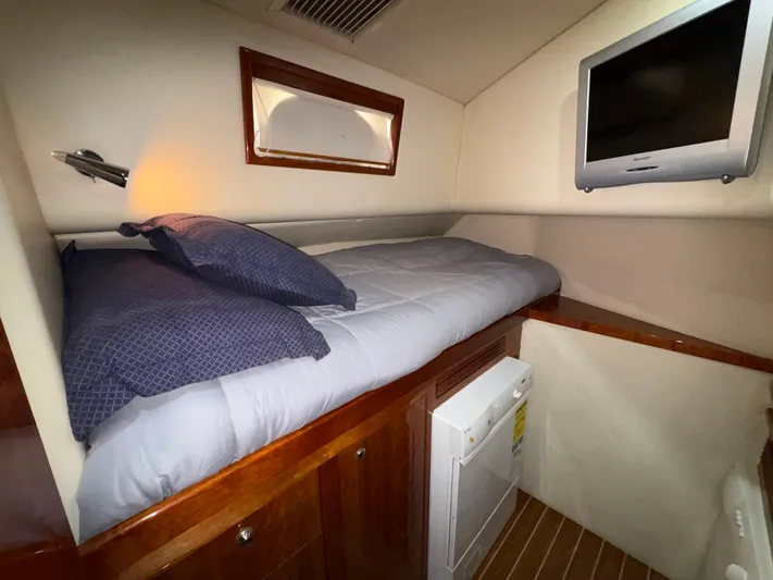 Obelix Yacht Photos Pics Cozy cabin interior of 2006 Riviera 60 Flybridge with bed and wall-mounted TV.