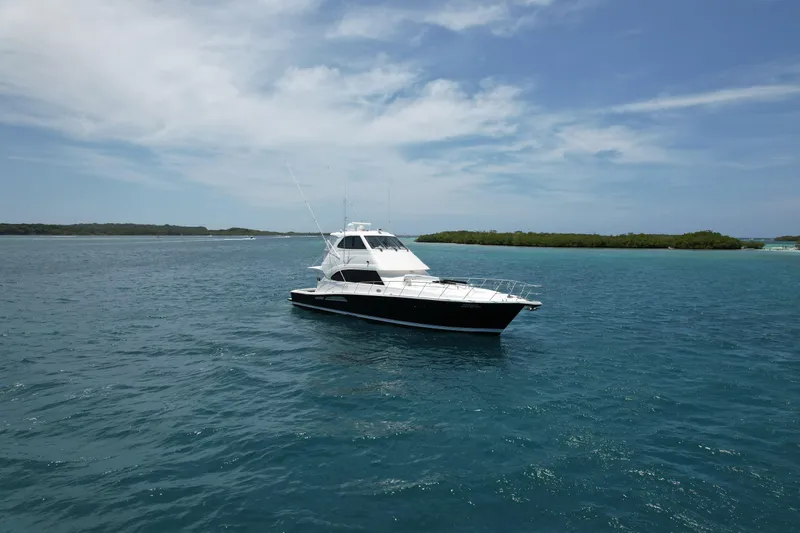 Obelix Yacht Photos Pics 2006 Riviera 60 Flybridge yacht cruising on clear blue waters under a partly cloudy sky.