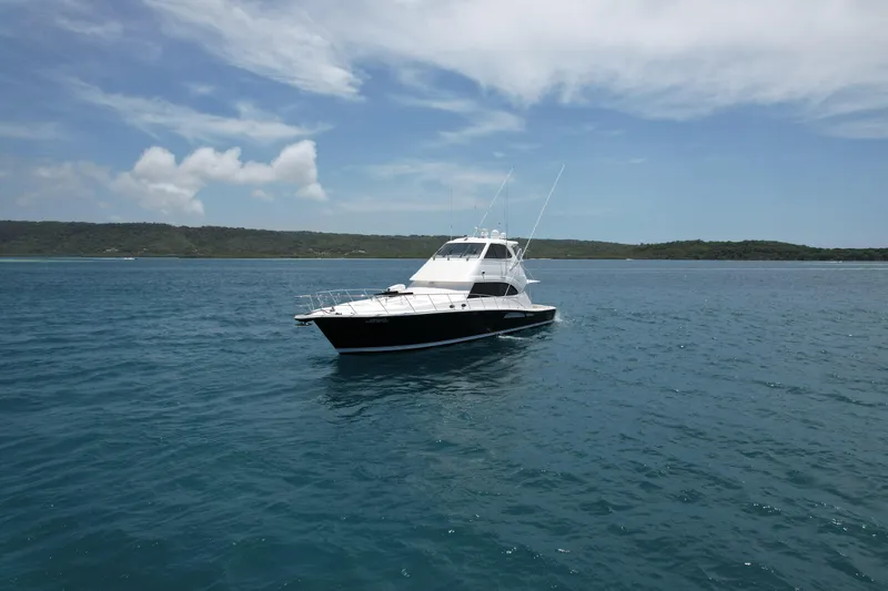 Obelix Yacht Photos Pics Riviera 60 Flybridge yacht from 2006 on calm blue waters under a clear sky.